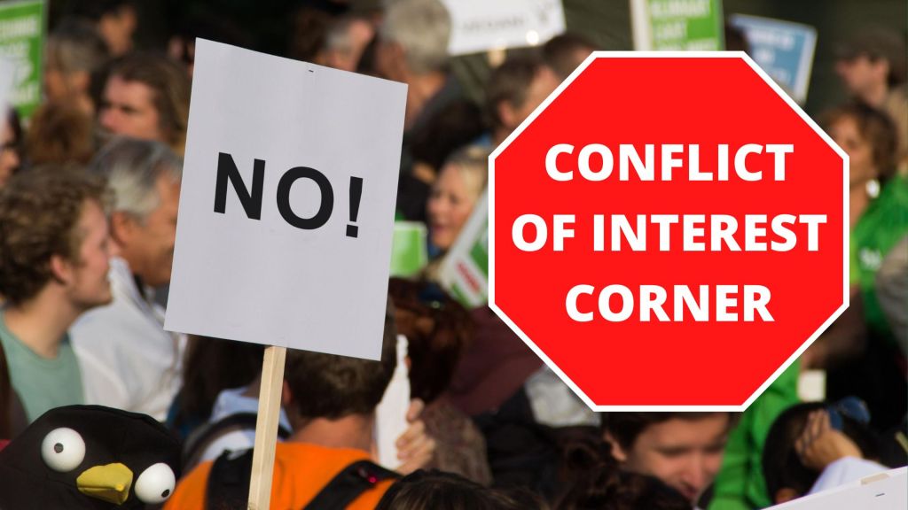 Depiction of a stop sign graphic reading "Conflict of interest corner" layered over a generic photo of a protest. A protest sign in the background simply reads "NO!" and the framing of a protestor's funny hat gives the implication a wide-eyes cartoon penguin is holding the sign. 